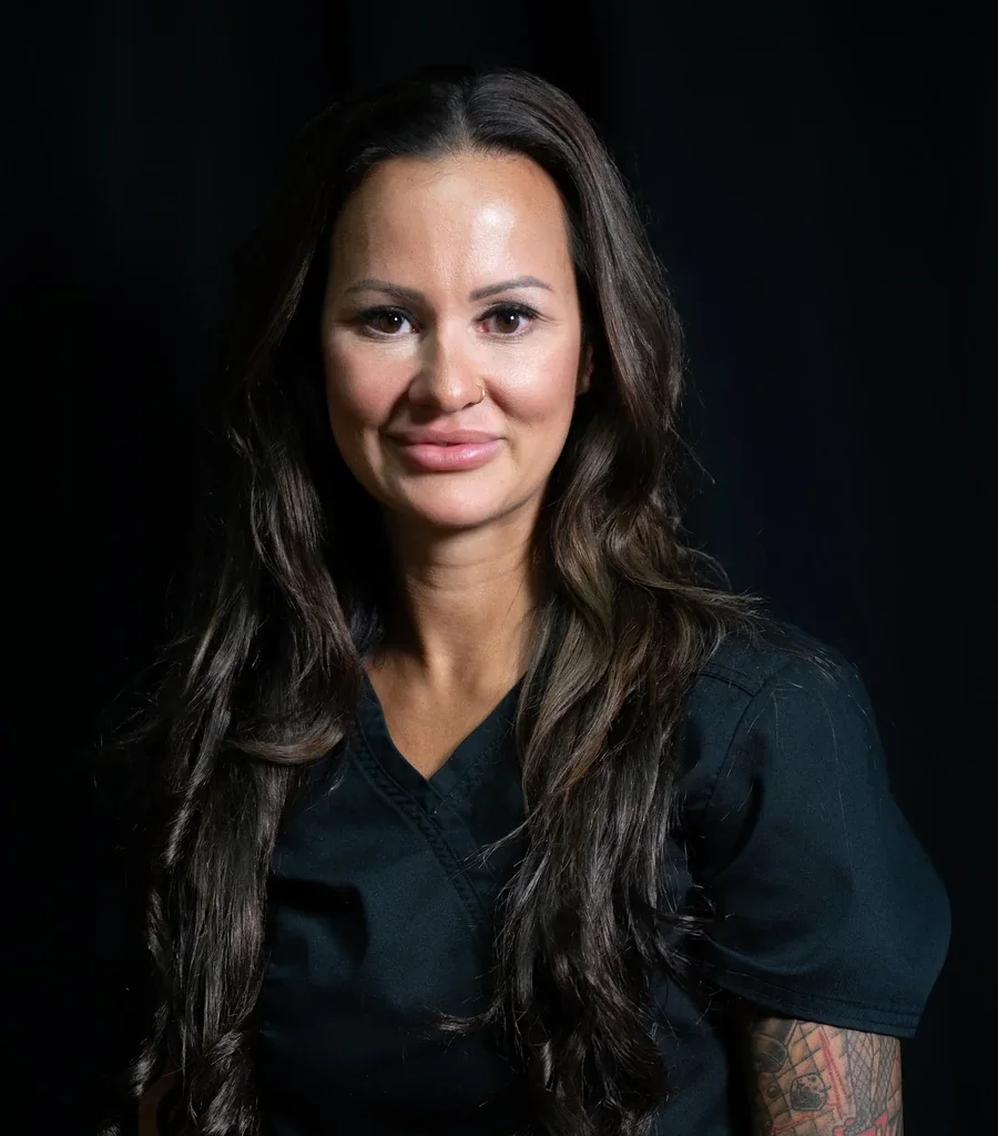 Nurse practitioner wearing medical scrubs in a clinical treatment environment.