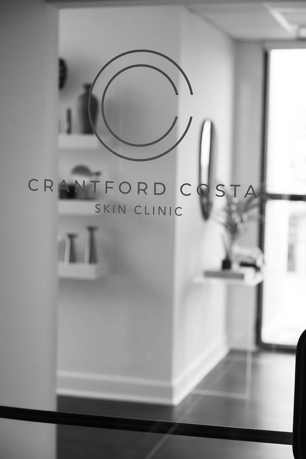 Circular logo and Crantford Costa Skin Clinic lettering on a glass door, shelves visible beyond