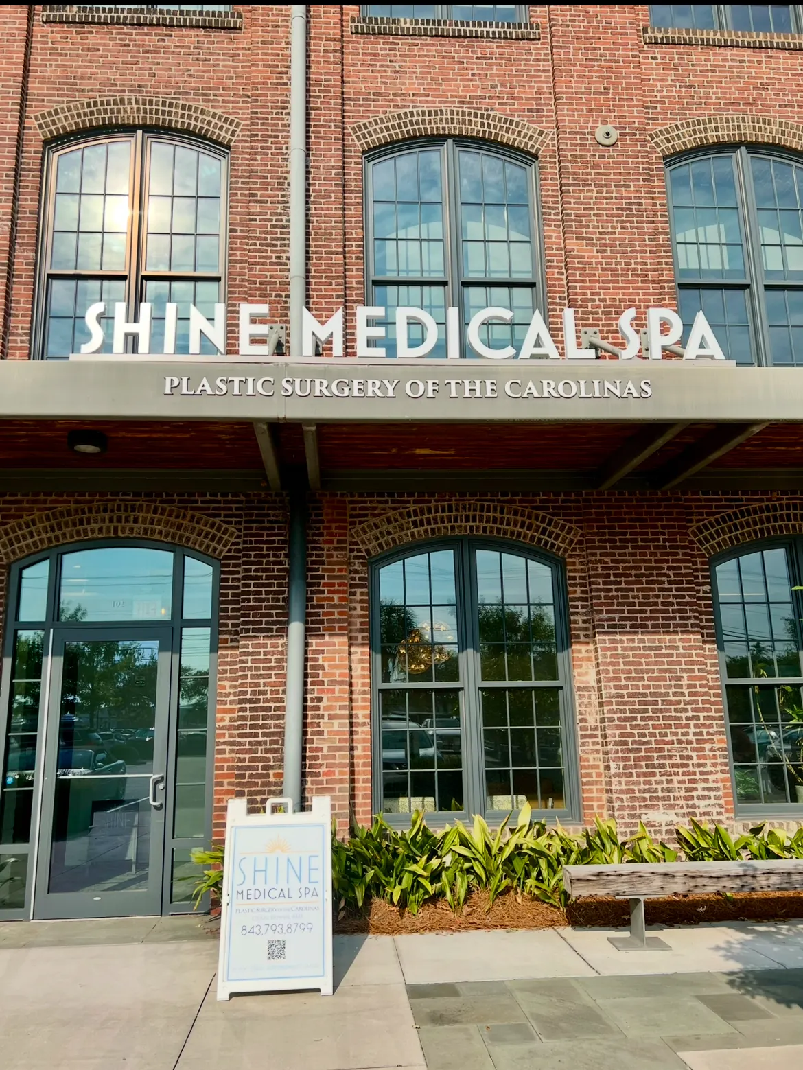 Brick entrance beneath SHINE MEDICAL SPA letters with a sandwich board beside the door