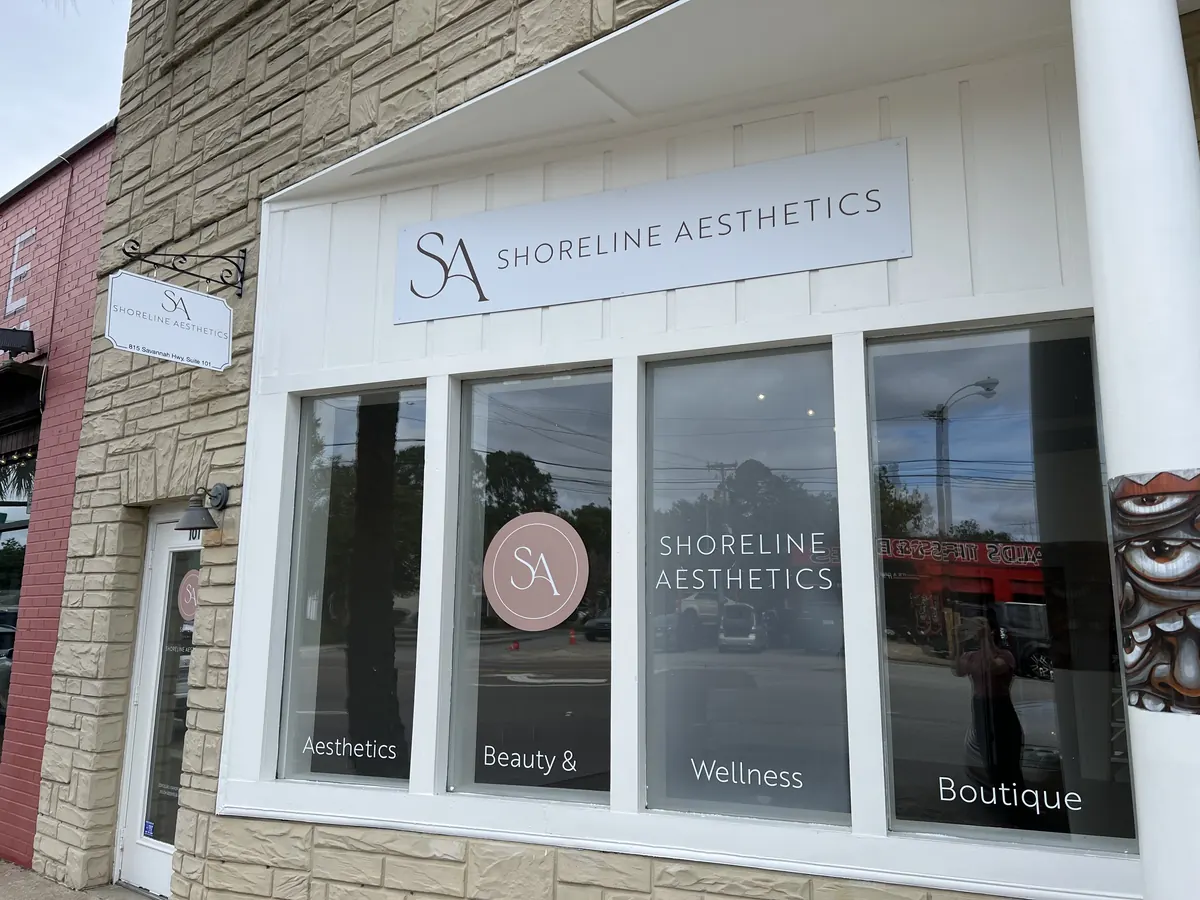 Storefront with Shoreline Aesthetics lettering, window graphics and a hanging bracket sign