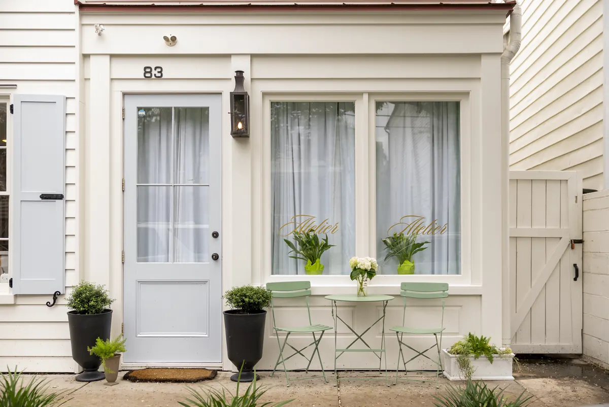Cottage entrance with a light blue door, bistro table and gold script window lettering