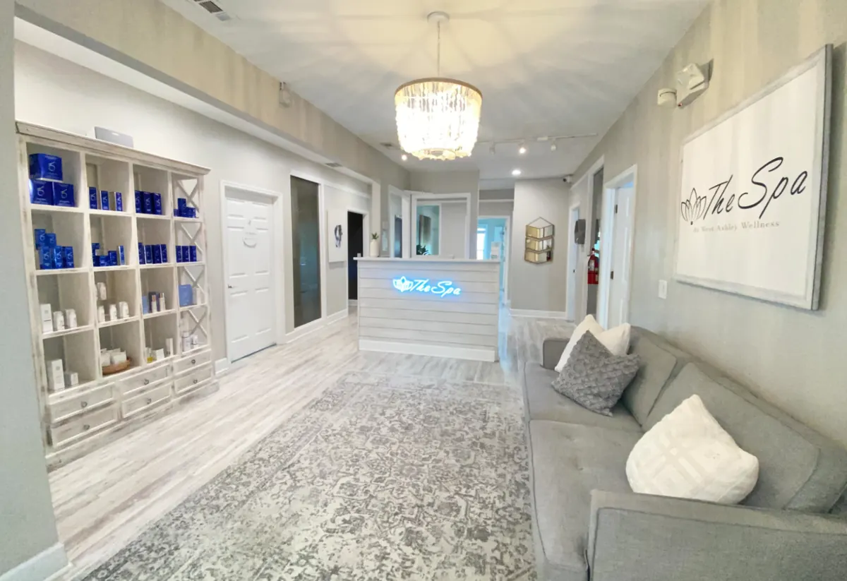 Lobby with reception desk, product shelving, gray sofa and a framed The Spa wall sign