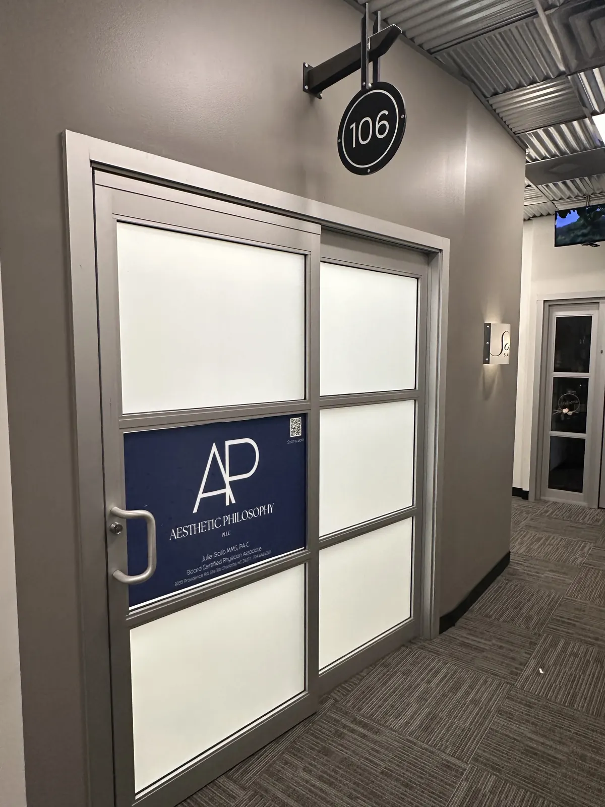 Frosted glass suite door with a blue Aesthetic Philosophy panel beneath a round 106 sign