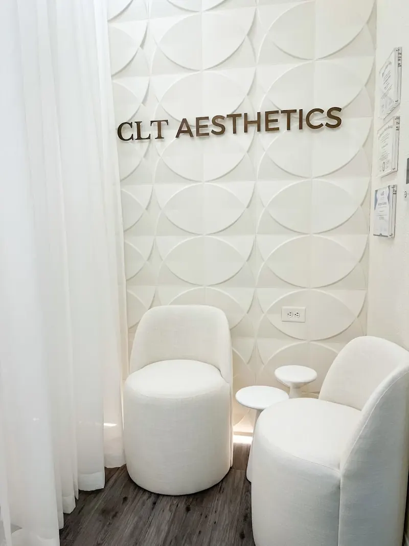 CLT Aesthetics lettering on a sculpted white wall panel above two white chairs