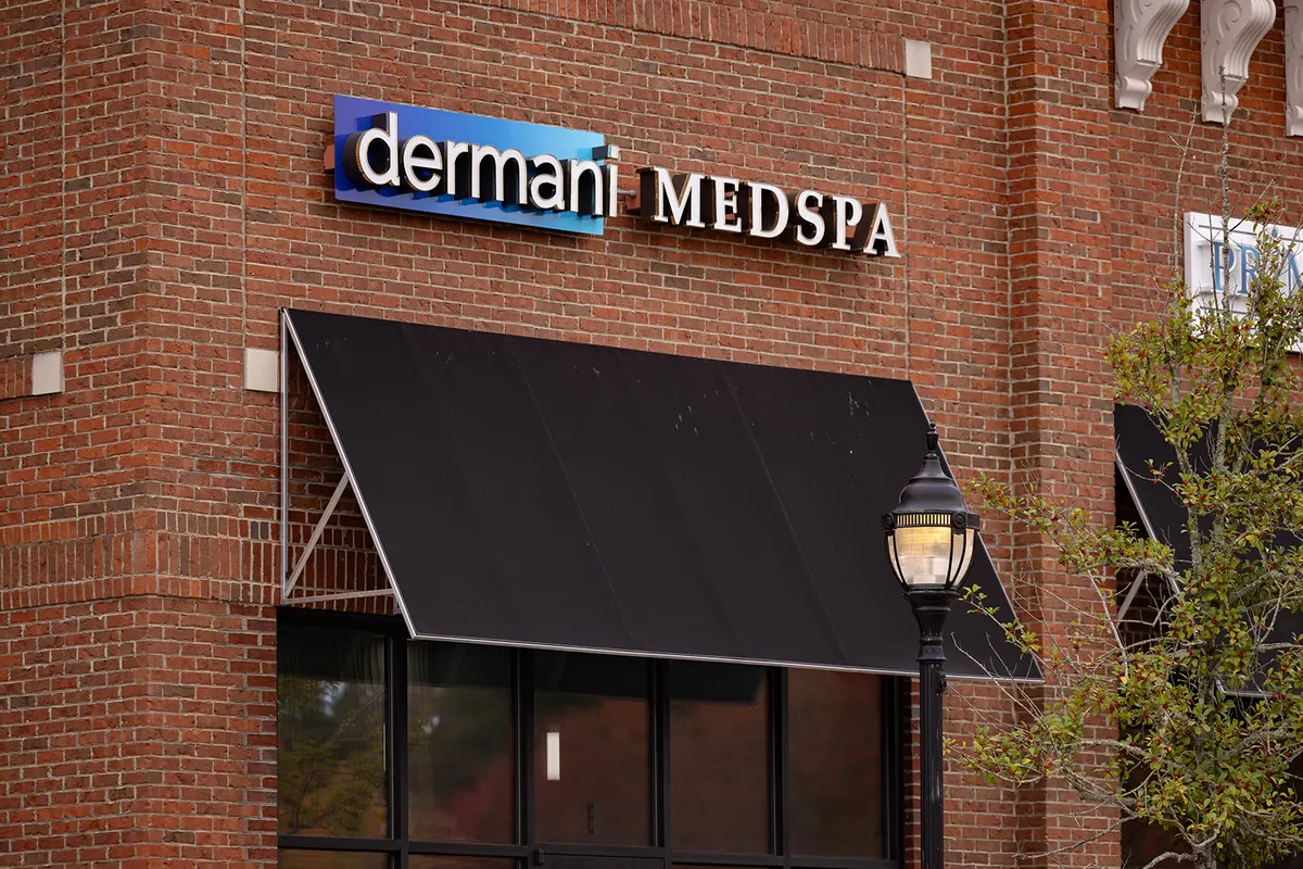 dermani MEDSPA sign above a black awning on a red brick storefront