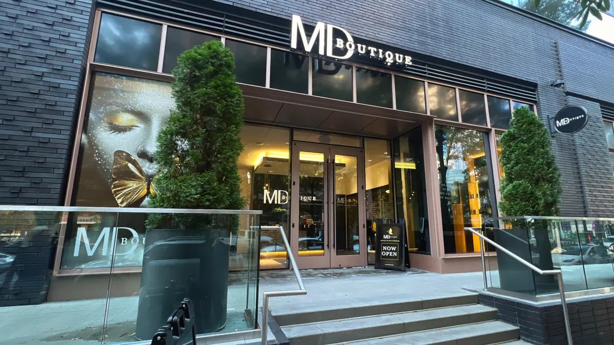 Storefront entrance with steps, glass railing and illuminated MD Boutique sign above the doors