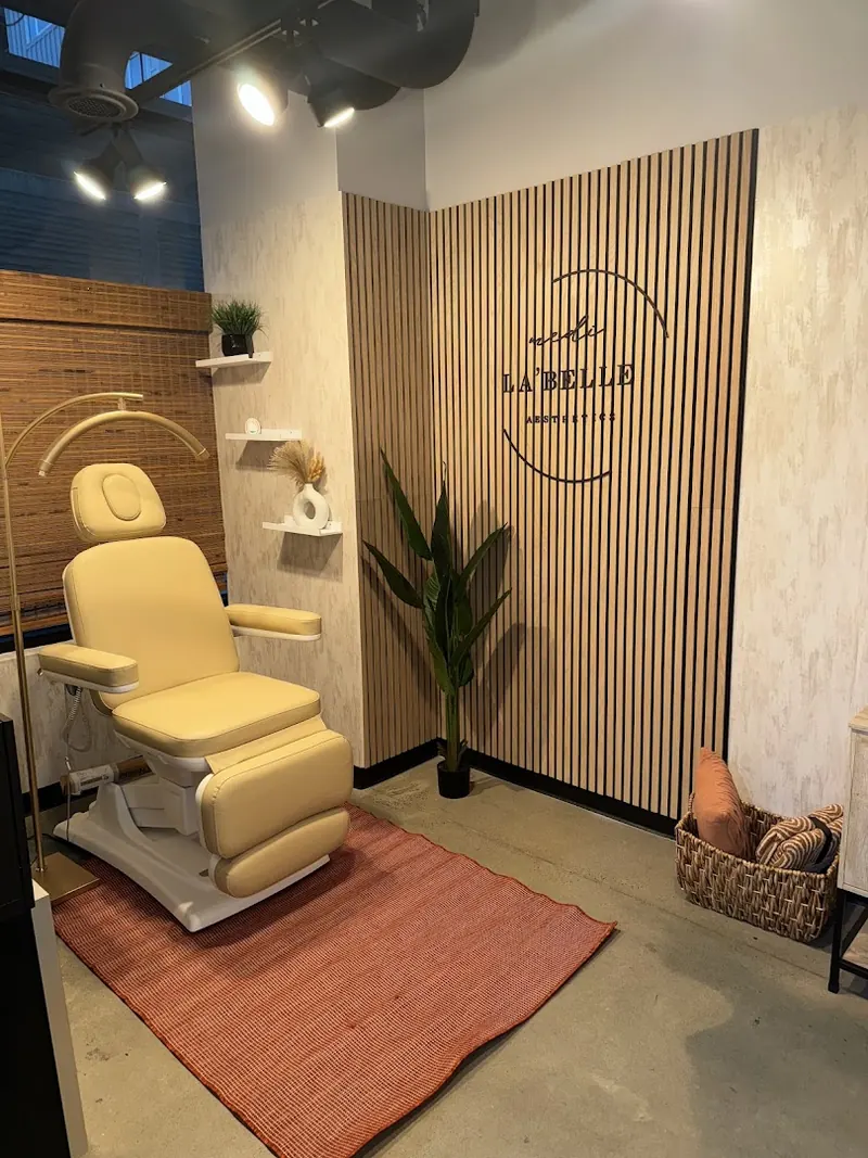 Cream treatment chair and terracotta rug beside a wood-slat wall with the Medi La'Belle Aesthetics logo