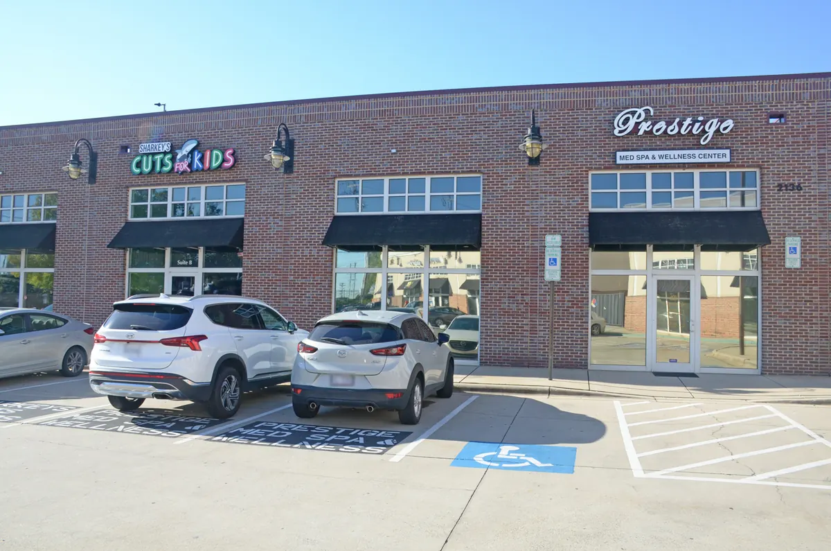 Brick storefront with Prestige Med Spa & Wellness Center sign above black awnings and a glass door