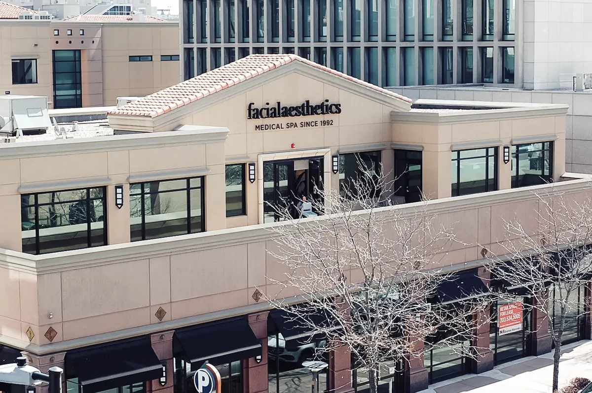Tan two-story building with a tile-roof gable signed facialaesthetics Medical Spa Since 1992