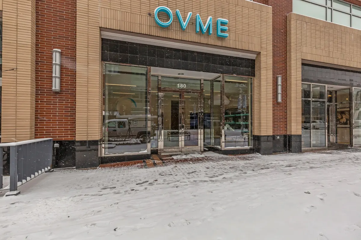 OVME storefront sign above glass entrance doors numbered 180 on a snowy sidewalk