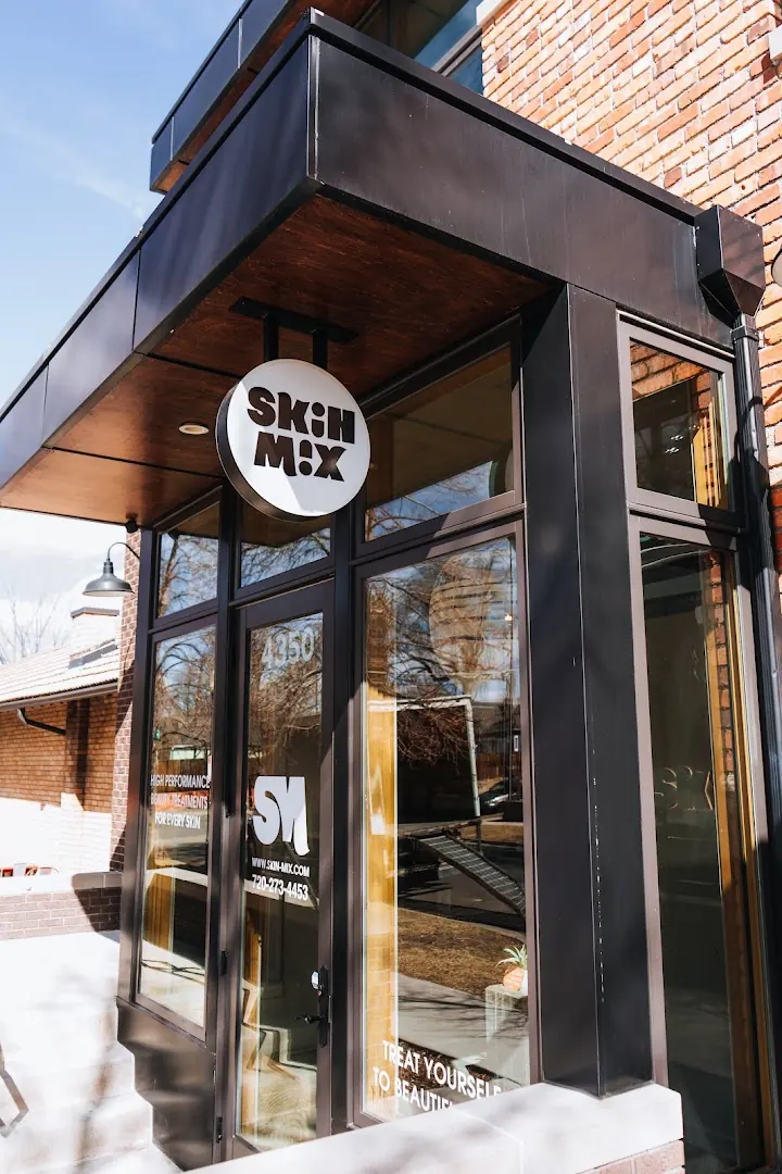 Glass storefront entrance under a round hanging Skin Mix sign with door number 4350