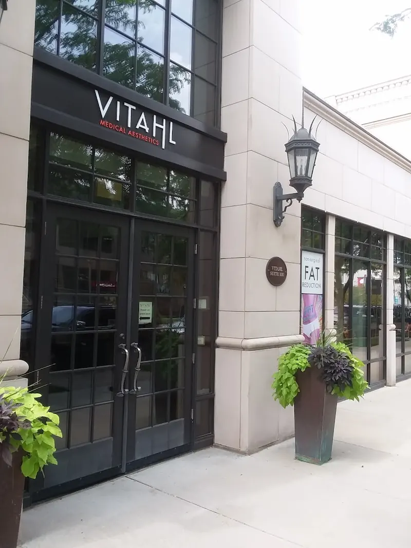 Black double doors under a VITAHL Medical Aesthetics sign with planters on the sidewalk
