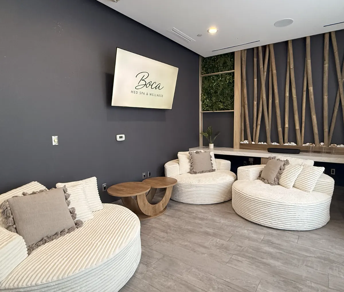 Cream round lounge seats facing a wall screen showing the Boca Med Spa & Wellness logo