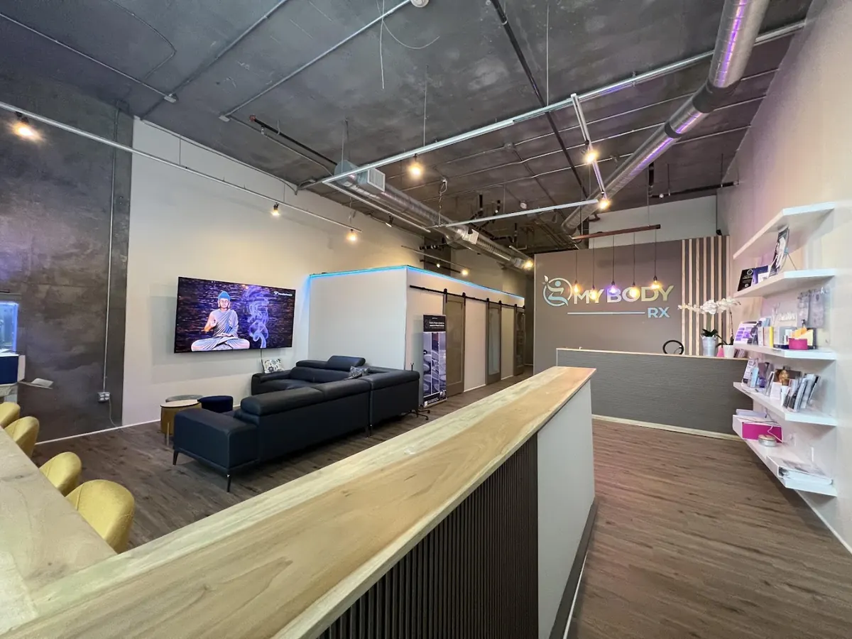 Loft-style lobby with My Body Rx sign behind reception, retail shelves and lounge sofa