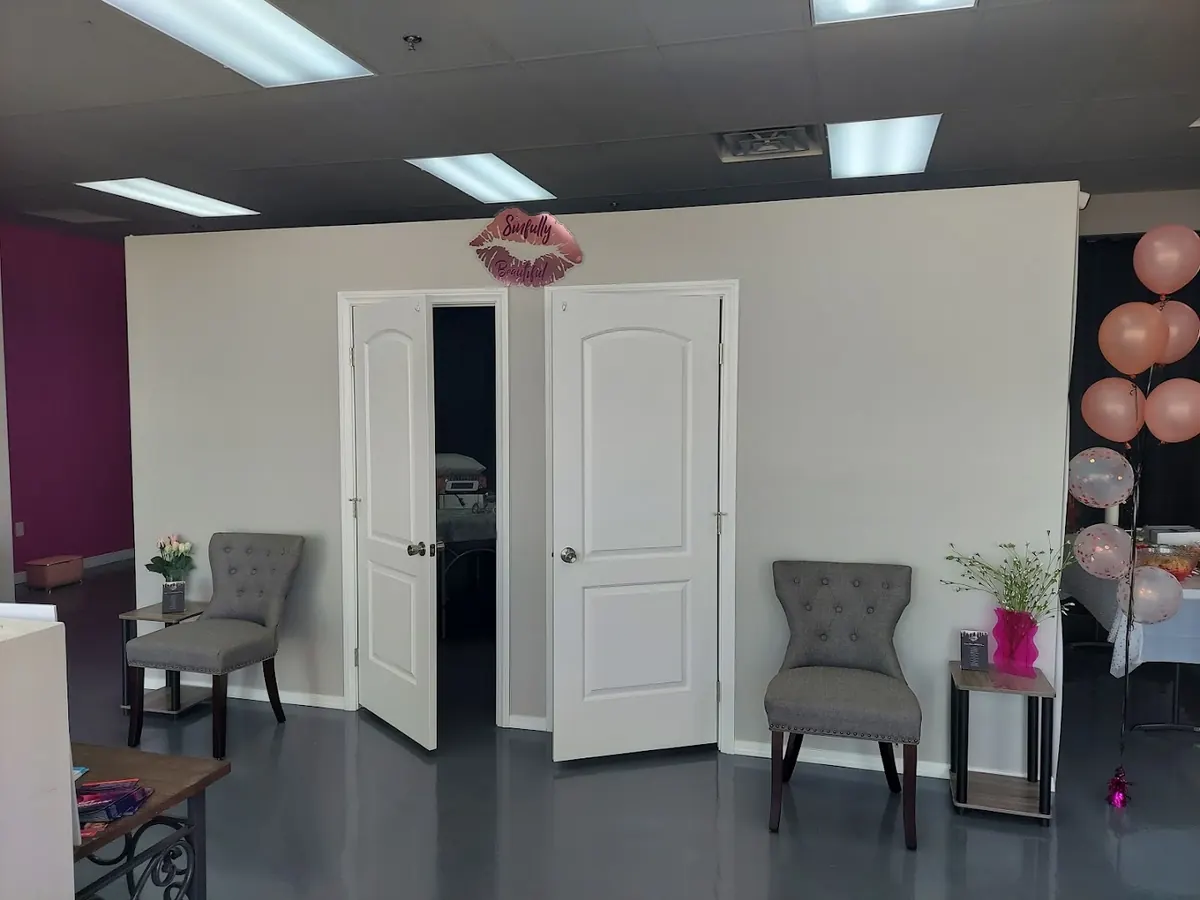 Lobby with Sinfully Beautiful lips sign above white double doors and grey tufted chairs