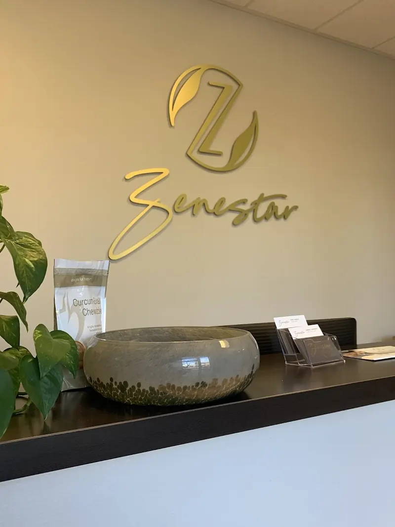 Gold Zenestar logo on the wall above a dark reception counter with a glass bowl