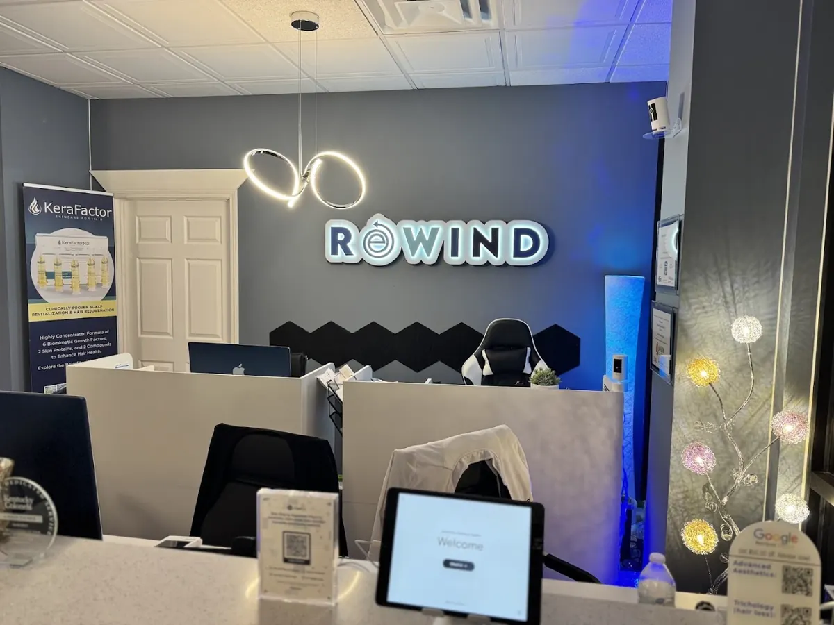 Reception counter facing a backlit Rewind wall sign and a looped pendant light