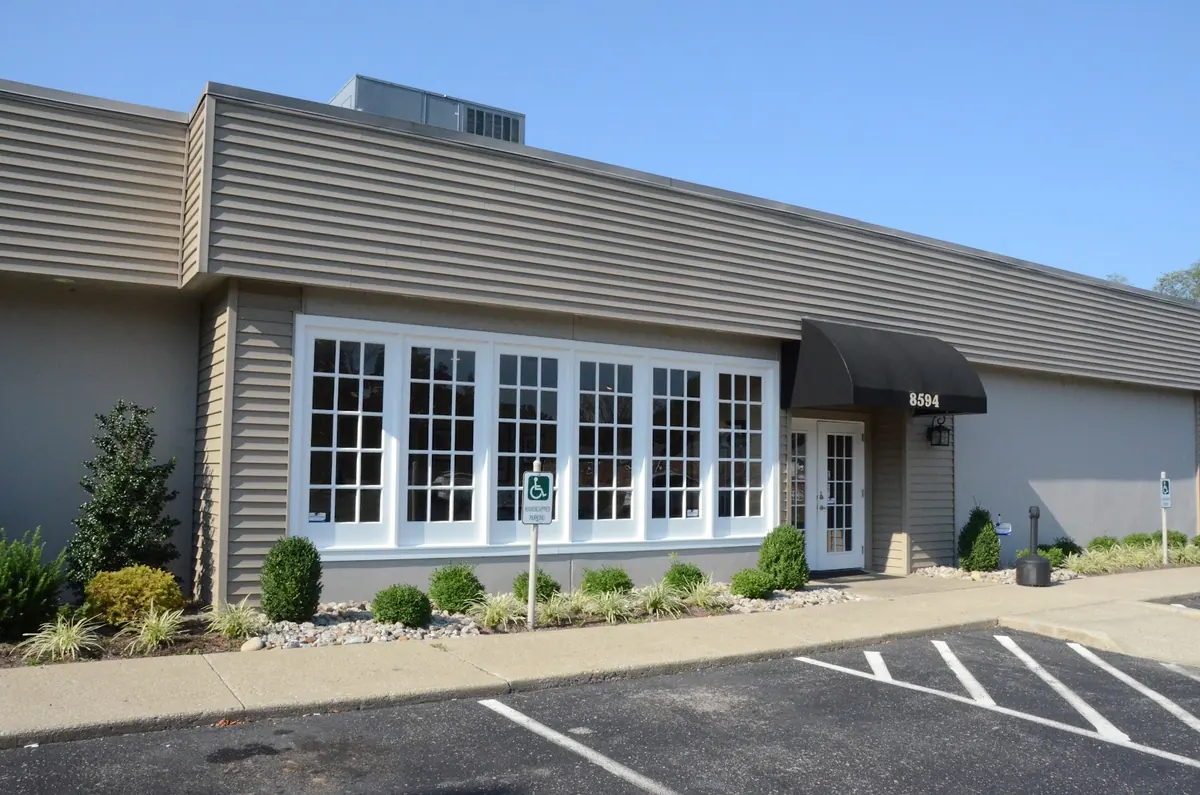 Single-story office building with multi-pane windows and a black awning marked 8594