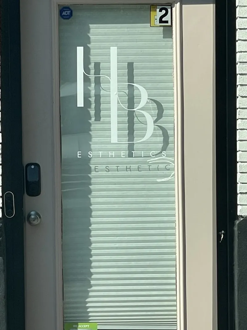 Glass entry door with an HB logo decal, closed blinds and a number 2 placard