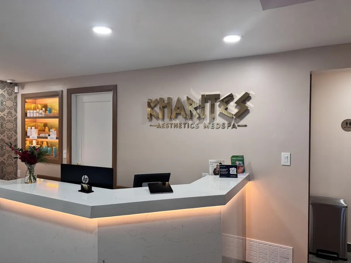 Gold Kharites Aesthetics Medspa lettering above a white reception desk with underlighting