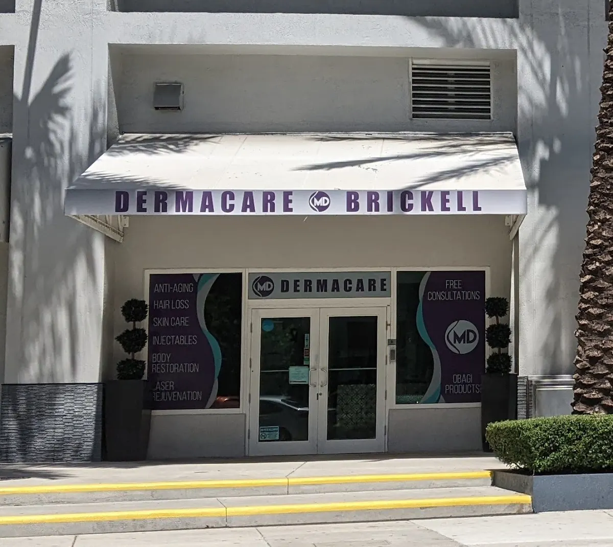 Dermacare Brickell storefront with a white awning, glass double doors and purple window panels