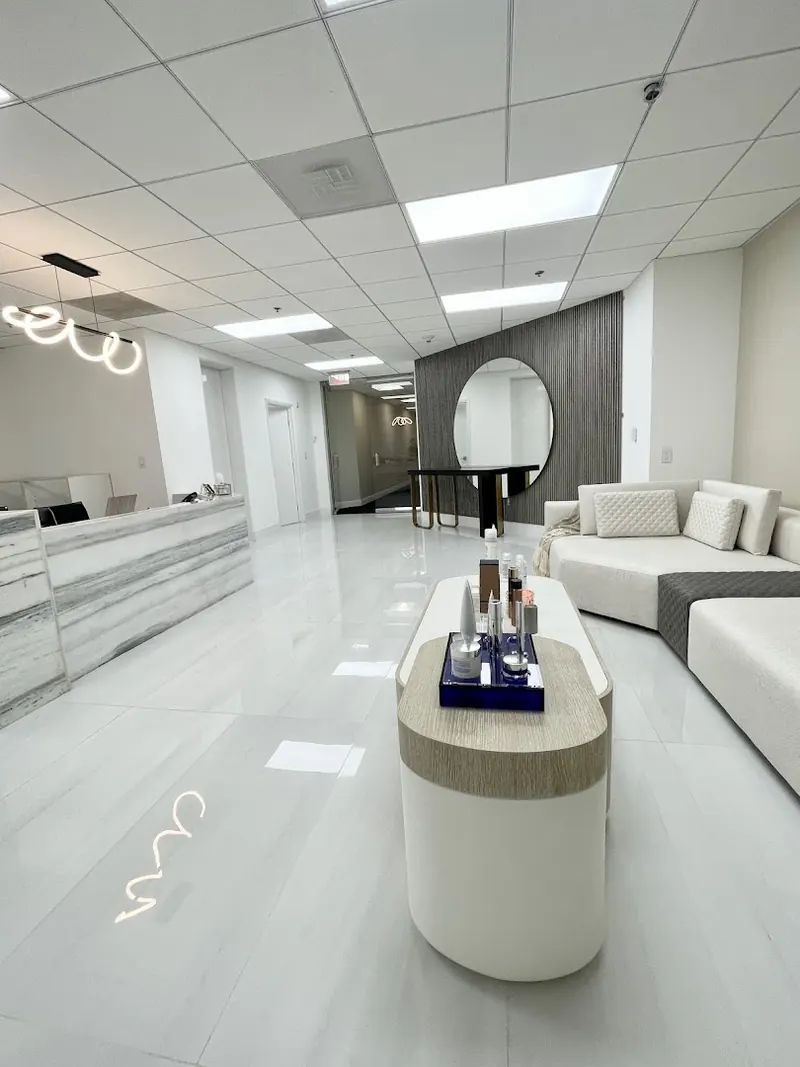 Reception lobby with marble-banded desk, cream sofas and a slatted wall with round mirror