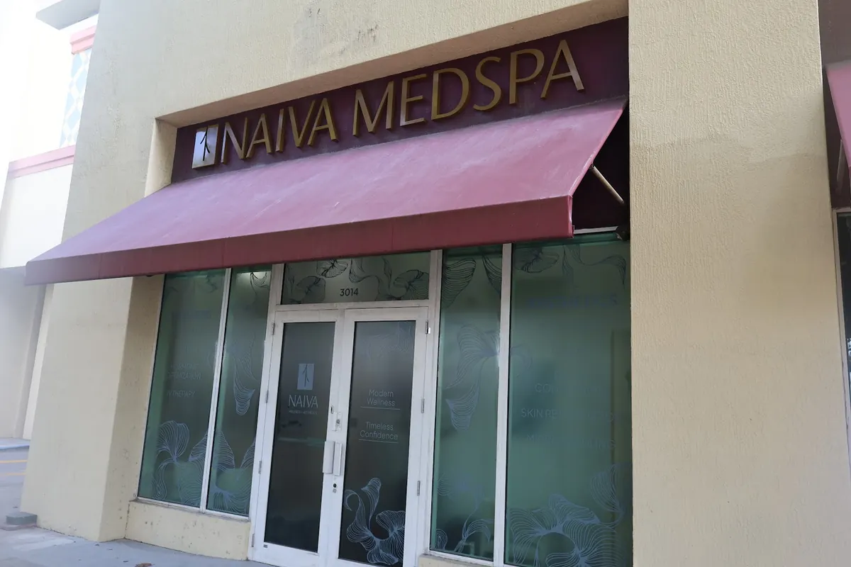 Naiva Medspa storefront with a maroon awning and frosted floral window film