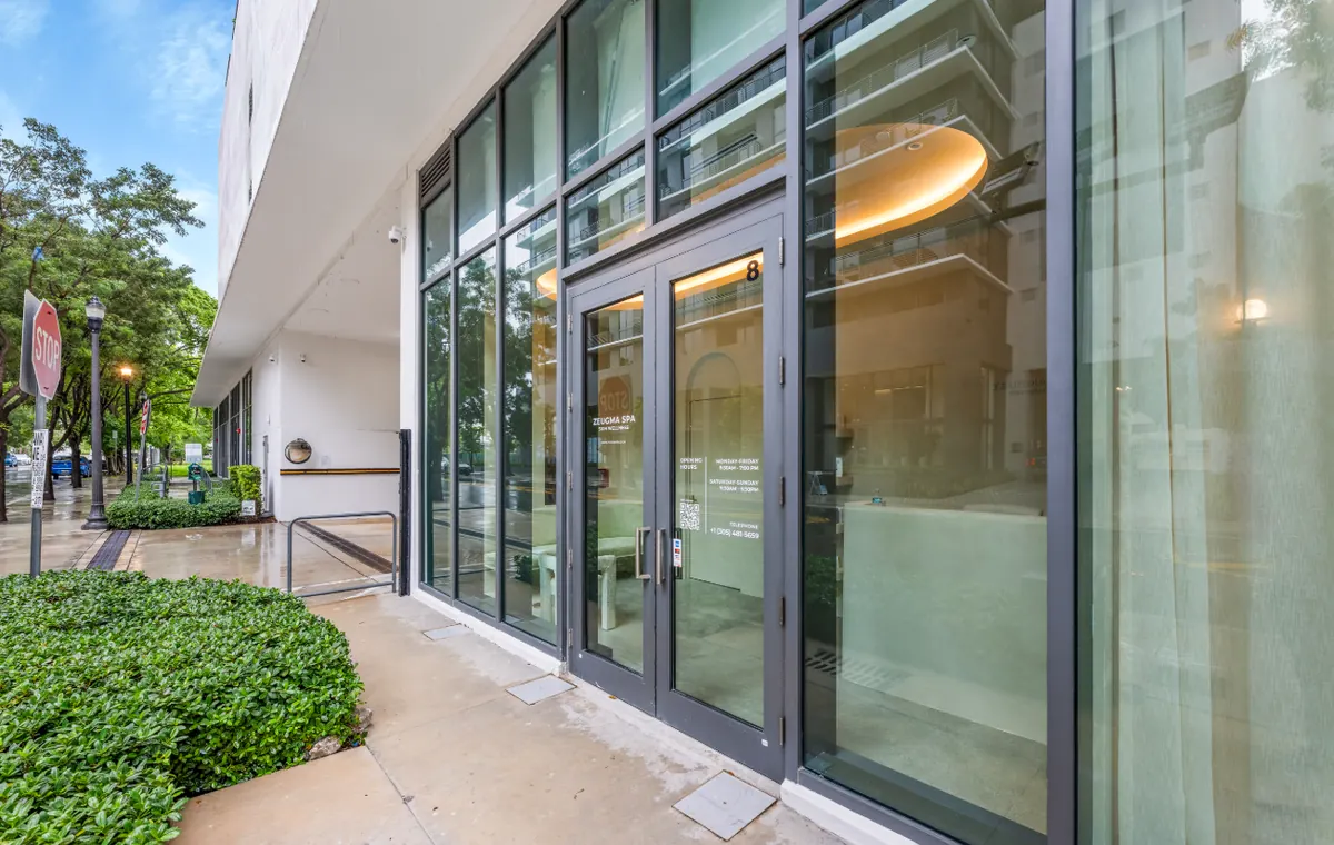 Glass entrance doors marked 8 with Zeugma Spa lettering and opening hours on the door