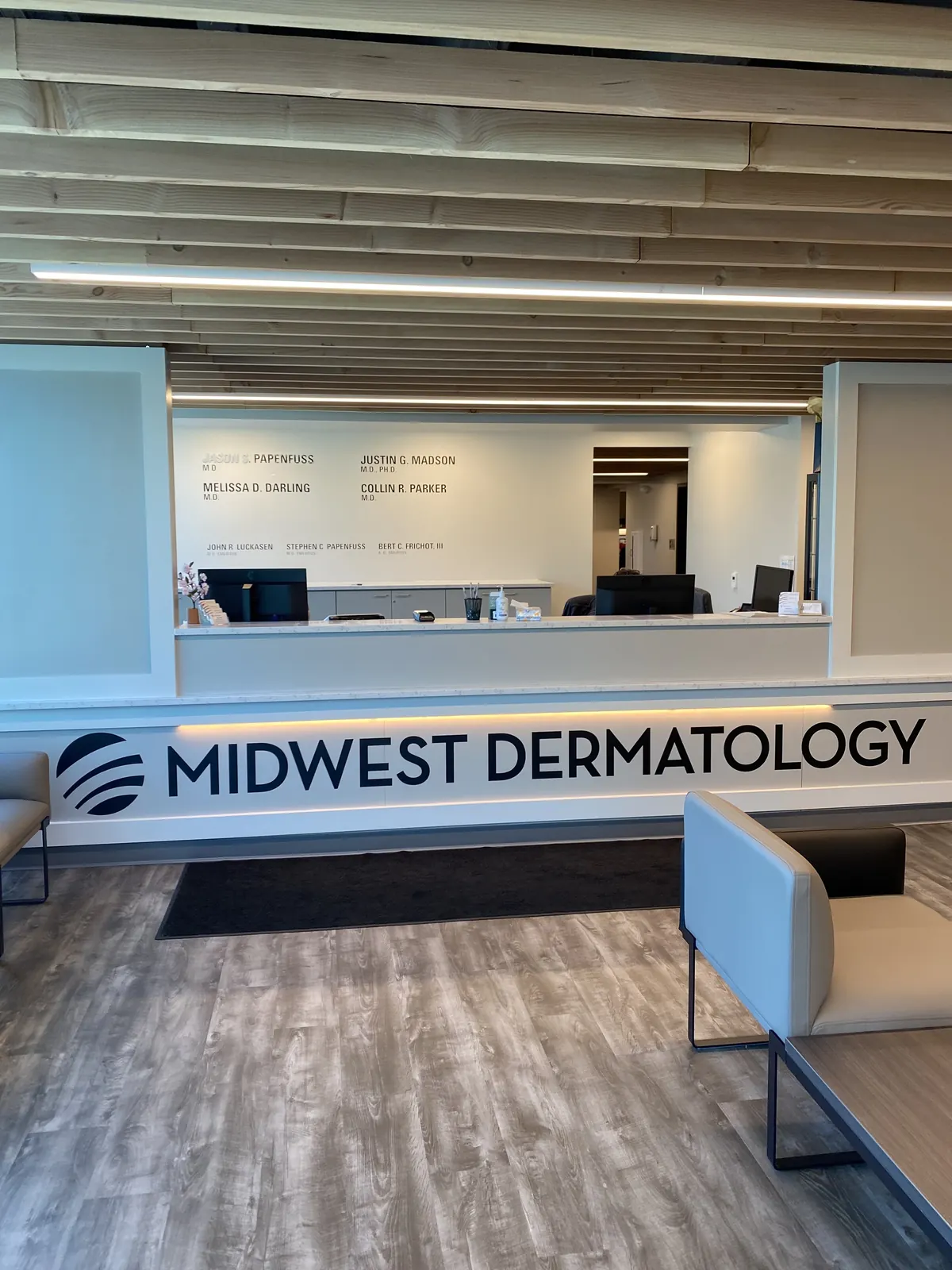 Reception desk with Midwest Dermatology lettering below a wall of staff names