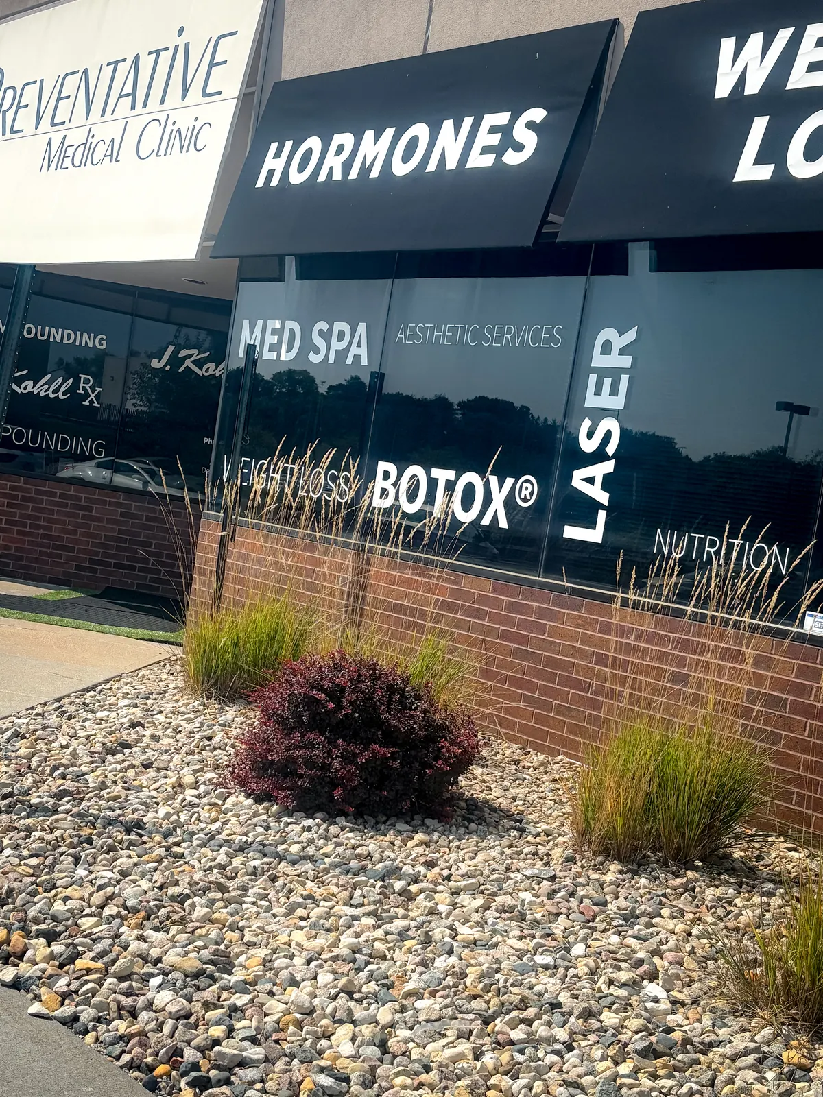 Brick storefront with Preventative Medical Clinic lettering and Hormones, Med Spa and Laser window signs