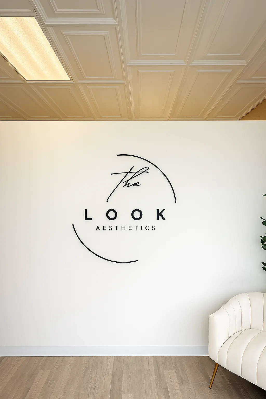 Wall logo reading The Look Aesthetics beside a cream accent chair