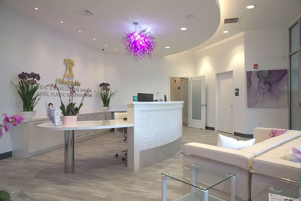 Reception desk and cream sofas under the gold Philadelphia Facial Plastic Surgery & Medspa sign