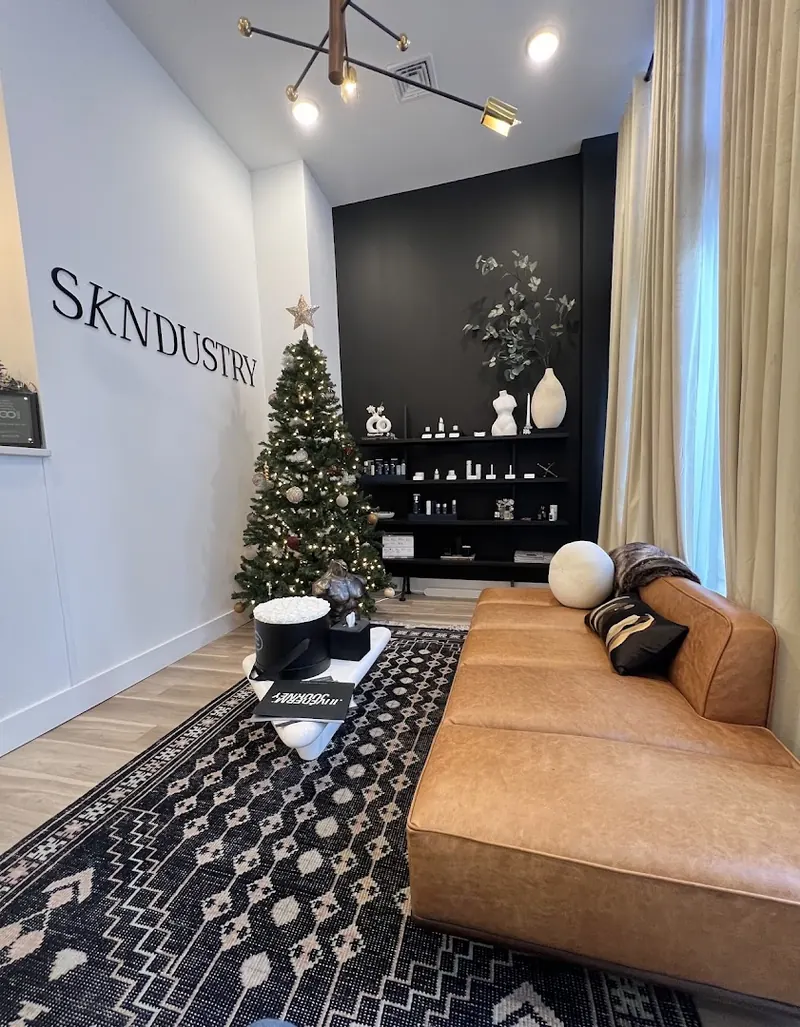 Lounge with tan leather sofa, patterned rug, black shelving and SKNDUSTRY wall lettering