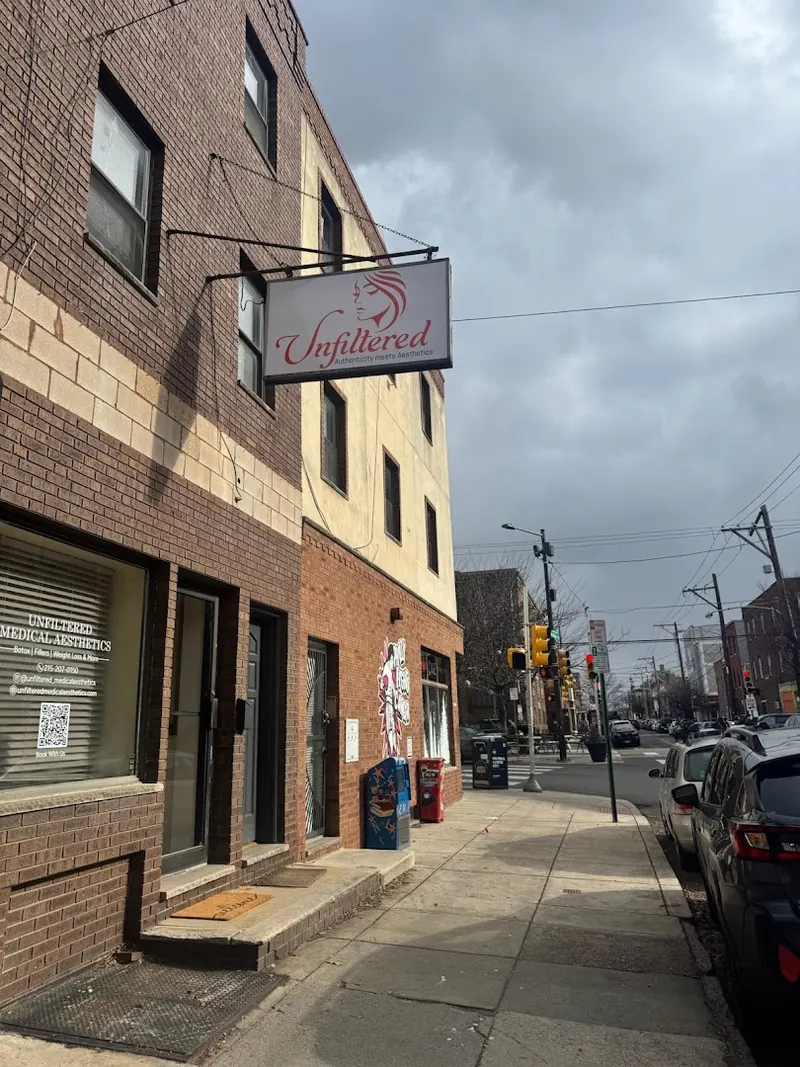 Brick row building with a hanging Unfiltered sign and Unfiltered Medical Aesthetics window lettering