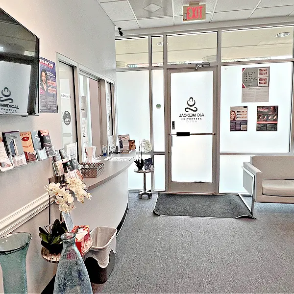 Reception counter and waiting area facing a glass door with the AJC Medical Aesthetics logo