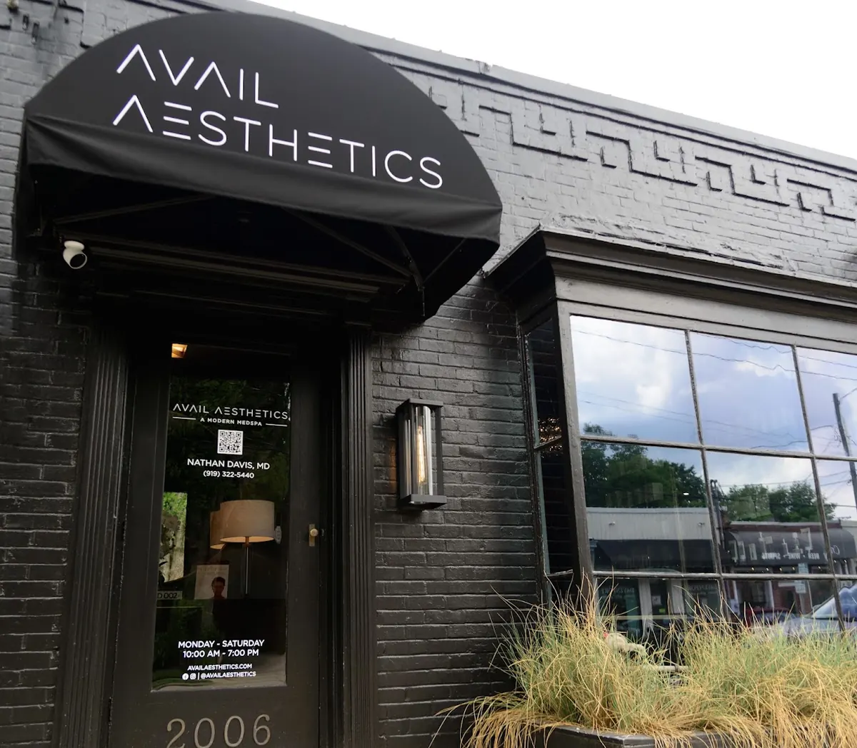 Black brick storefront with a black awning reading Avail Aesthetics above a glass door and the number 2006