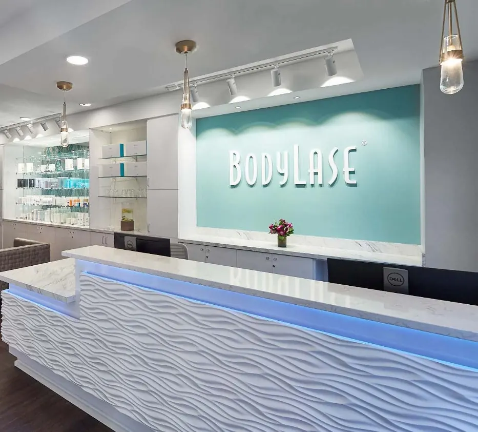 White wave-textured reception desk below a BodyLase wall sign on a teal panel
