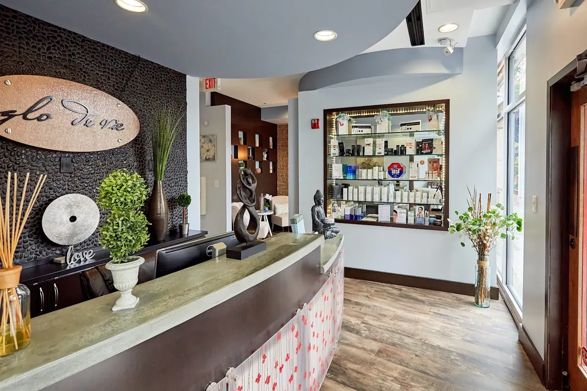 Curved reception counter and lit product shelves below a Glo de Vie wall sign