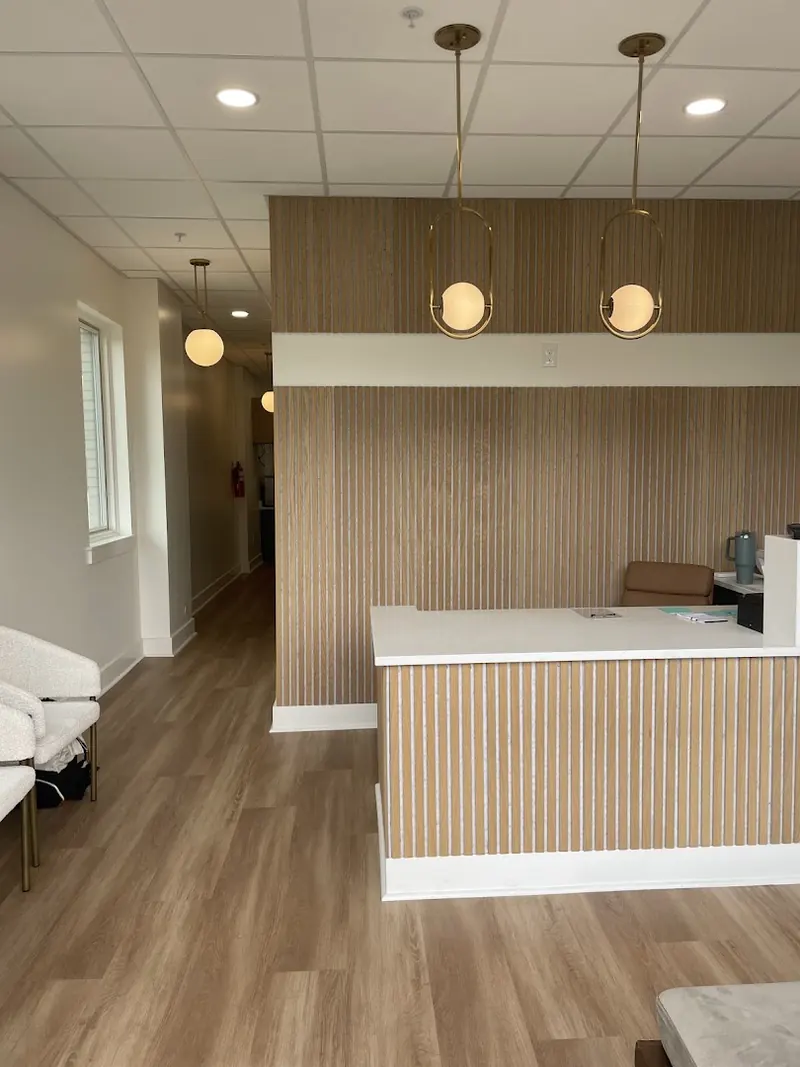 Reception counter with vertical wood slat paneling, a white top and gold globe pendant lights