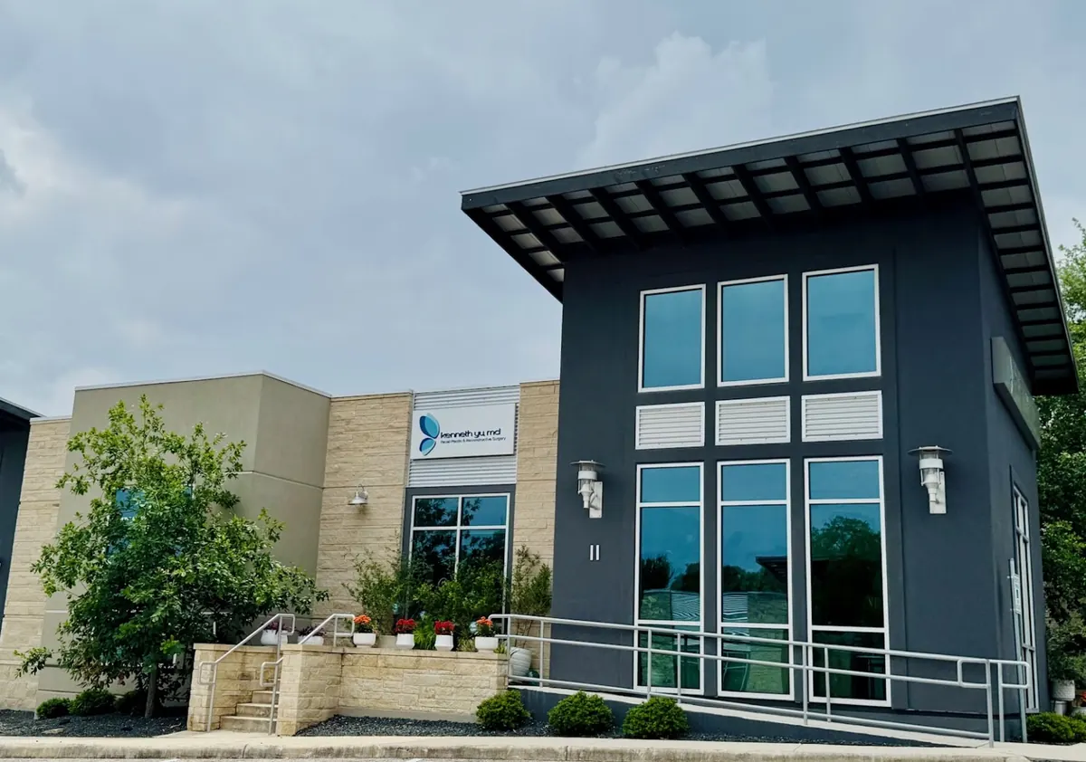 Charcoal building with tall windows, entry ramp and Kenneth Yu MD sign beside it
