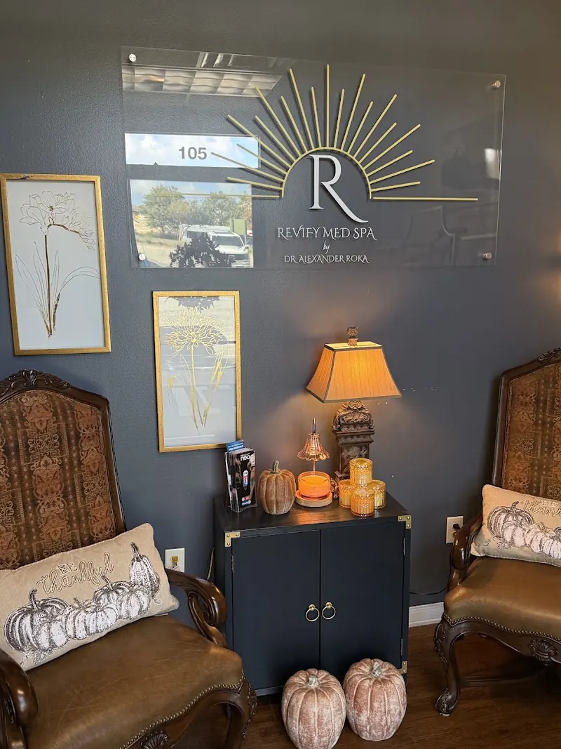 Waiting nook with carved armchairs, lamp and Revify Med Spa acrylic wall sign