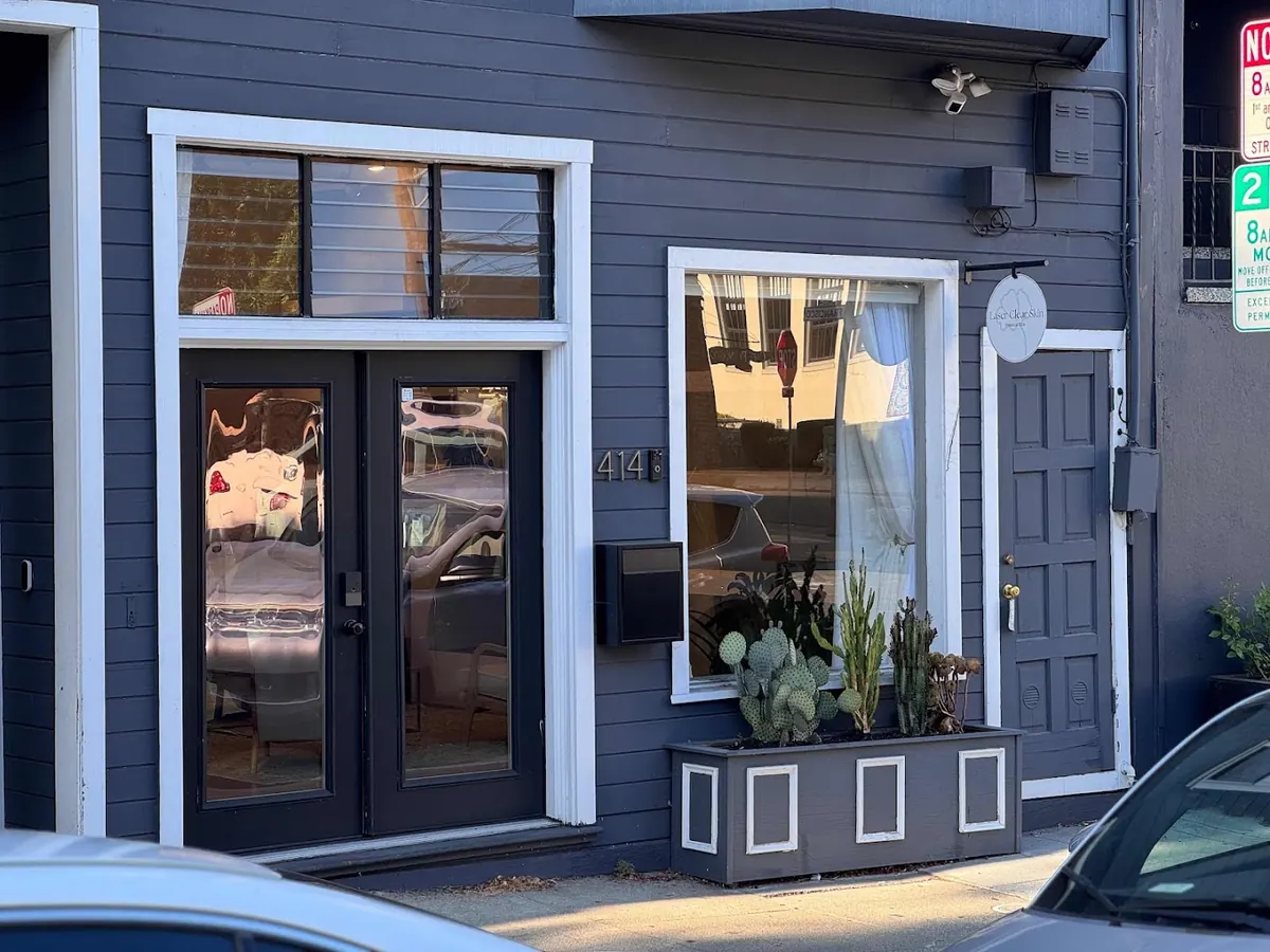 Navy clapboard storefront with double glass doors, number 414 and a round hanging sign