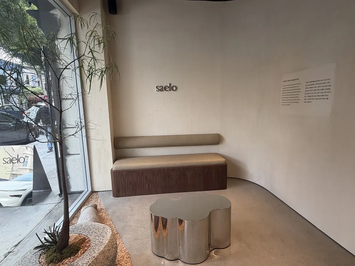 Lobby bench and mirrored table under a small metal saelo logo on a curved wall